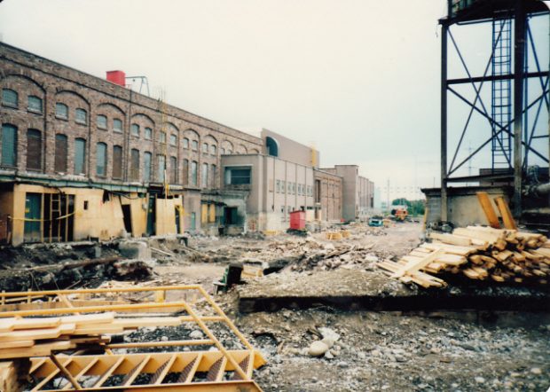 Chantier de construction, atelier d'usinage à gauche, gravier et poutres de bois à l'avant plan.