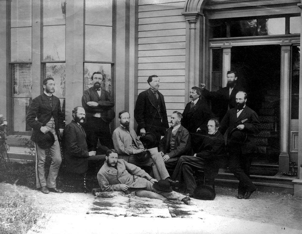 Une photo en noir et blanc de Walter Moberly et de dix autres hommes d’une équipe d’arpentage du CP. Les hommes sont vêtus de complets et sont répartis en trois rangs approximatifs devant un édifice. L’un des hommes est étendu sur le côté au premier rang. Le deuxième rang est constitué de quatre hommes assis, et le troisième rang de six hommes debout.