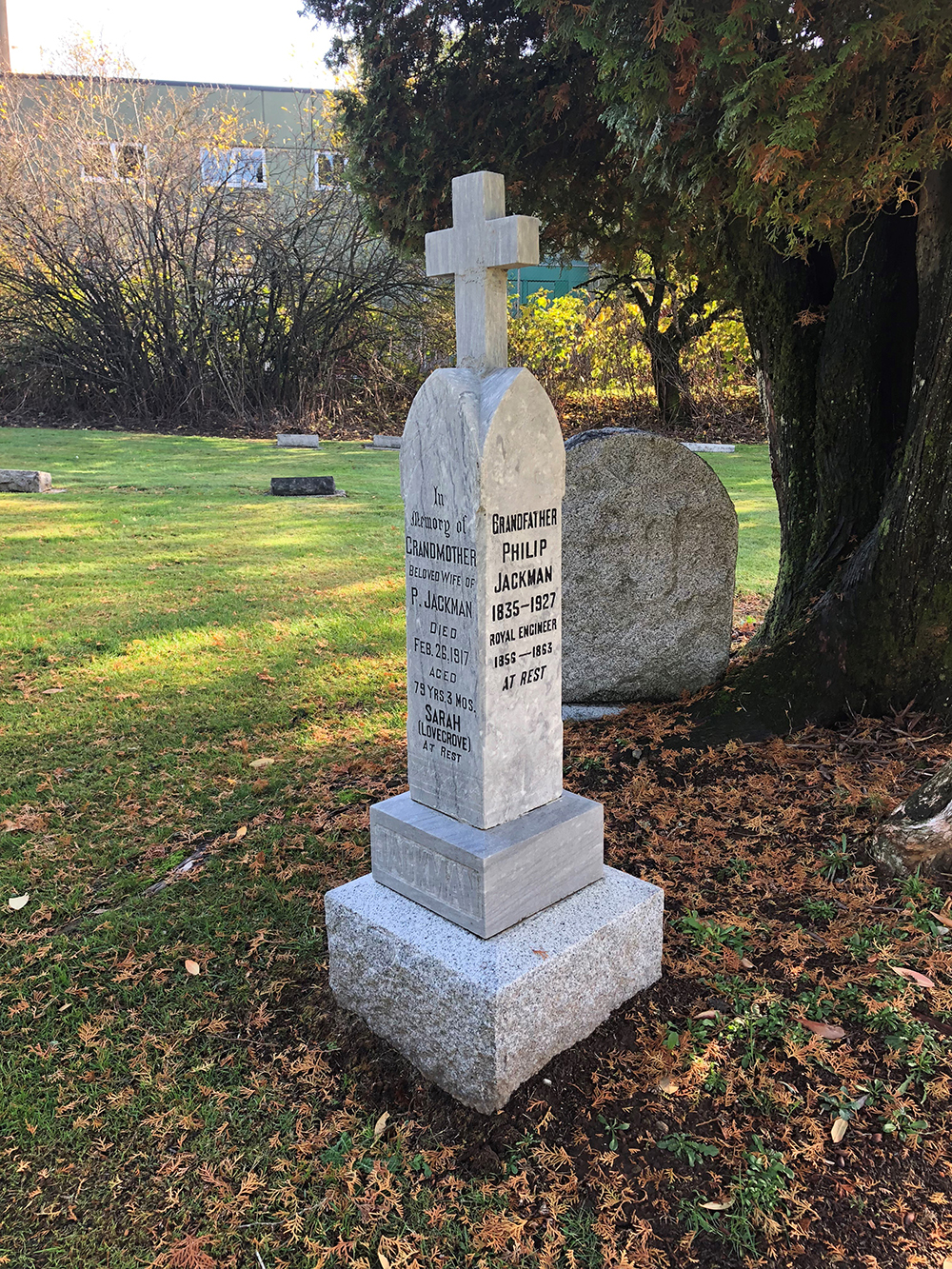 Photographie d’une pierre tombale à quatre faces dans un cimetière. La surface visible de gauche commémore la vie de Sarah Ann Lovegrove et celle de droite la vie de Philip Jackman. 