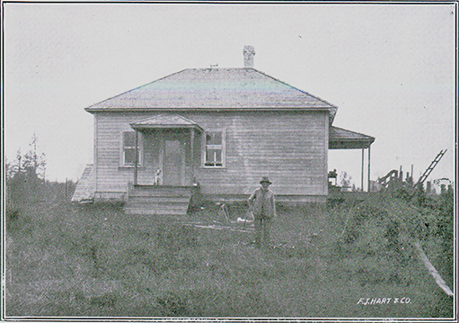 Photographie en noir et blanc d'un homme s'appuyant sur une canne, debout devant une maison. Il y a un escalier de cinq marches qui mène à l'entrée avant de la maison. Un chien est assis devant la porte d'entrée