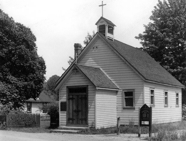 Photographie en noir et blanc d'une petite église dont le clocher est surmonté d'une croix.