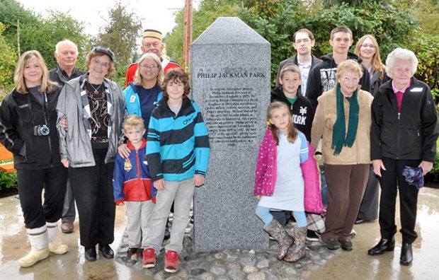 Photographie en couleur d'hommes, de femmes et d'enfants réunis autour d'une pierre commémorative portant un texte gravé. On y lit : « Philip Jackman Park » (Parc Philip Jackman).