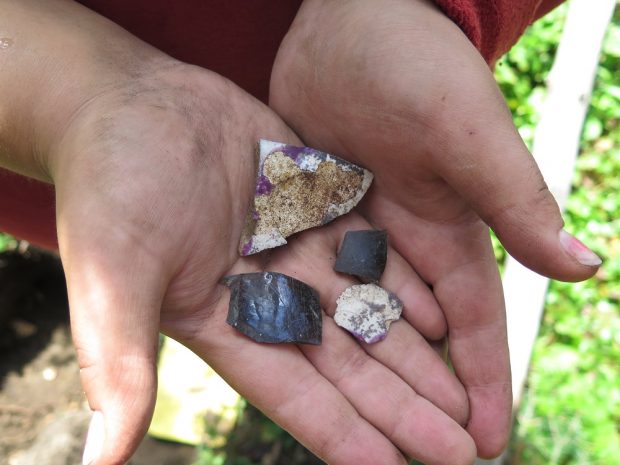 Deux tessons de céramique et deux fragments de verre dans des mains