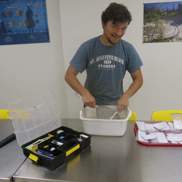 Personne nettoyant des artefacts dans un bac blanc avec une brosse à dent