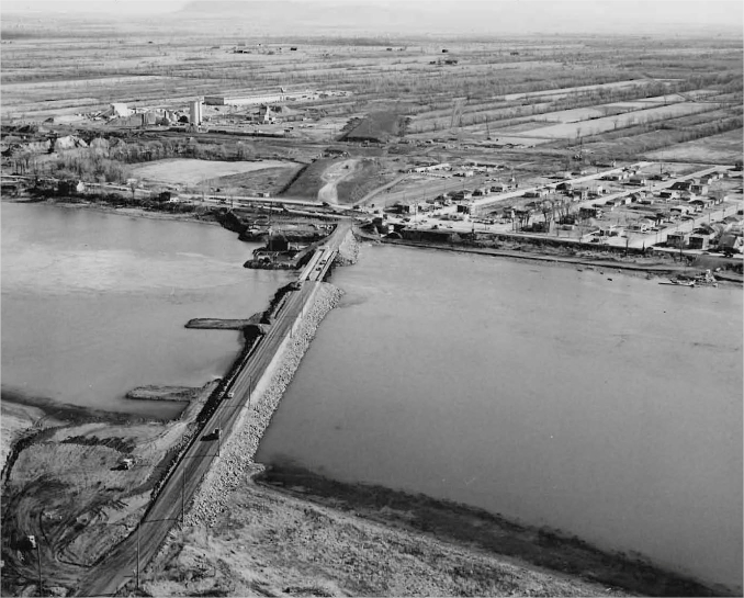 Un pont sur un cours d'eau avec une petite ville et des terres agricoles en arrière plan