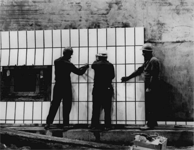 Trois hommes installant de la céramique sur les parois d'un tunnel