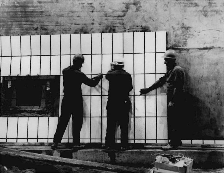 Trois hommes installant de la céramique sur les parois d'un tunnel