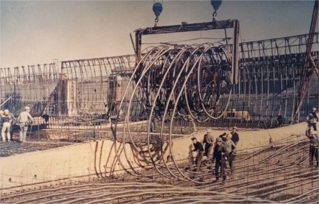 Des ouvriers déroulant des bobines d'acier dans une structure