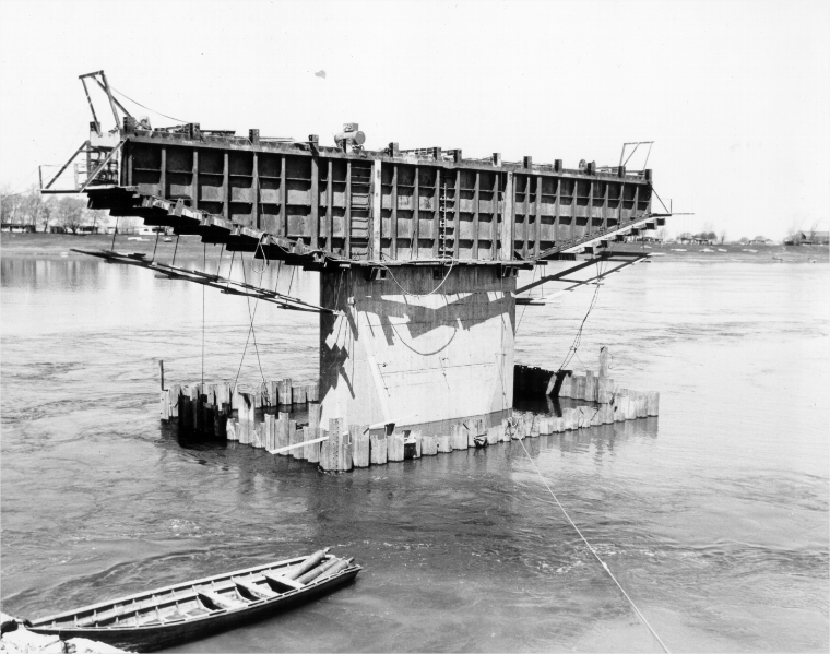 Un pilier de pont en construction avec une chaloupe en premier plan