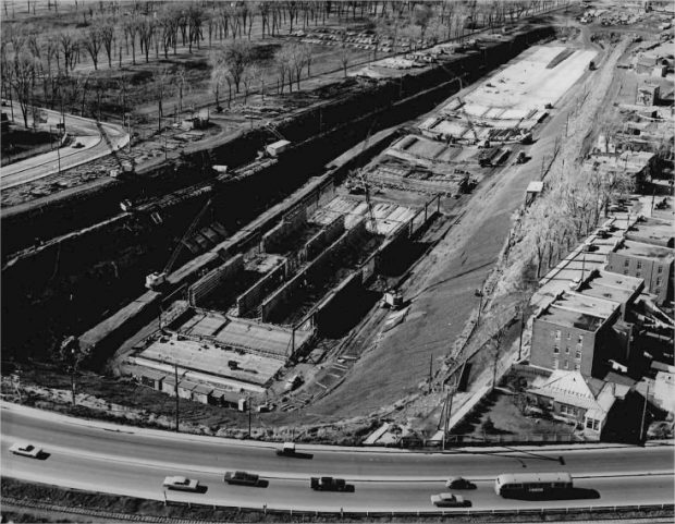 Une structure en construction avec des bâtiments et des voitures en circulation sur une rue