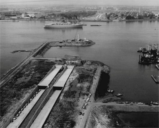 Une autoroute en construction près d'un cours d'eau avec un bateau et une ville en arrière plan