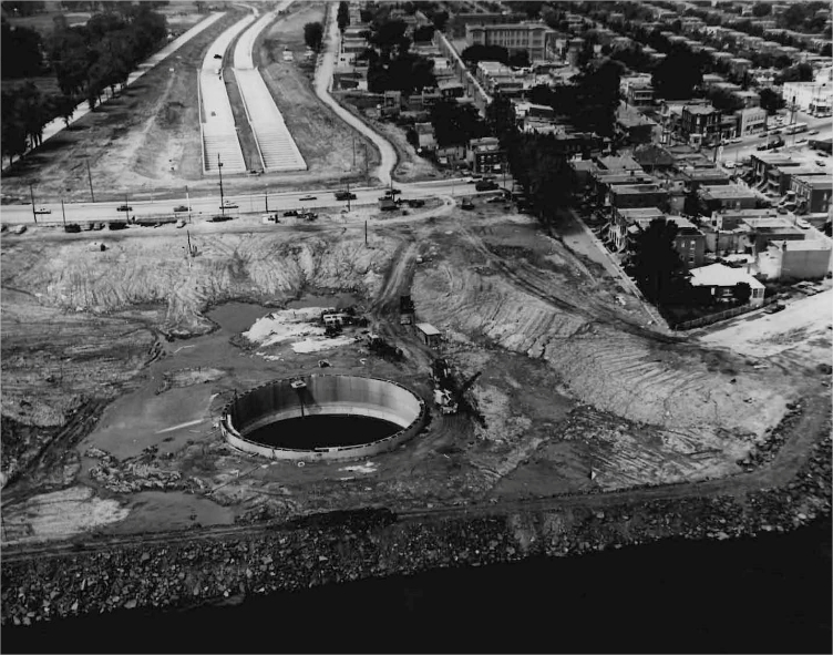 Une autoroute en construction avec un trou béant près d'une ville et d'un cours d'eau