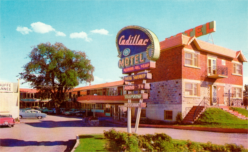 Un motel avec une affiche des années 1950 et des voitures stationnées