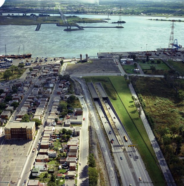 Des voitures circulant sur une autoroute avec des installations portuaires et un cours d'eau en arrière plan