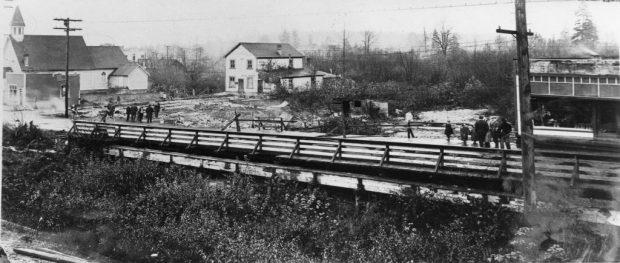 Une petite foule de gens rassemblés des deux côtés d’un pont endommagé.