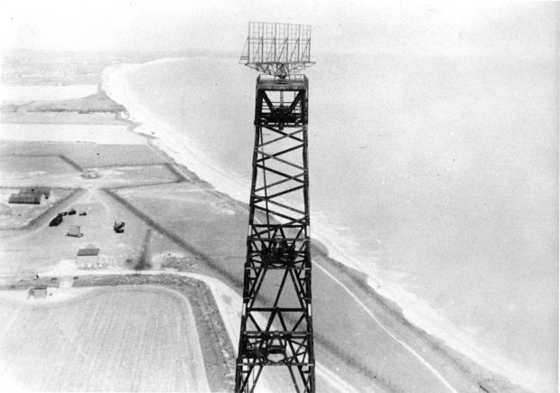Image en noir et blanc d’une tour radar avec vue sur la campagne et l’océan.