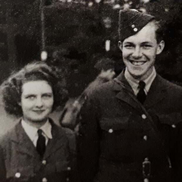 Photo en noir et blanc d'un jeune couple en uniforme des Forces aériennes de la Seconde Guerre mondiale, faisant sourire à la caméra.