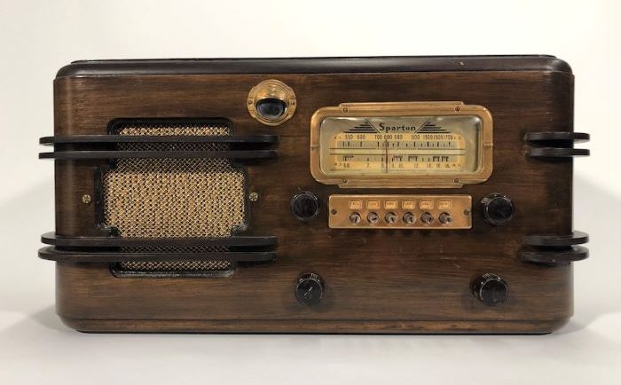 Radio Sparton en bois avec quatre cadrans, un meuble et un haut-parleur sur le côté, le tout avec des détails en laiton.