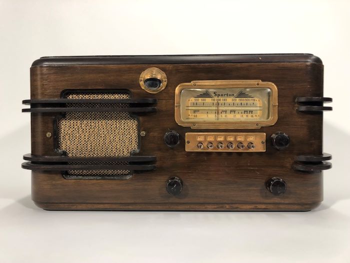 Radio Sparton en bois avec quatre cadrans, un meuble et un haut-parleur sur le côté, le tout avec des détails en laiton.