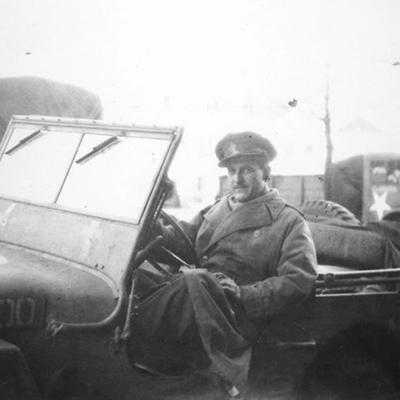 Photographie en noir et blanc du journaliste de la CBC/ SRC Marcel Ouimet dans une jeep militaire. Photographie prise vers 1944.