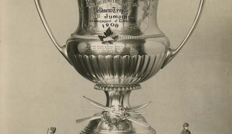 Grande coupe en argent sur un socle en bois ornée de part et d’autre de deux statues de skieurs.