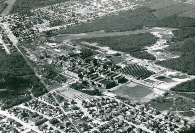 Photographie en noir et blanc démontrant une vue aérienne de l’usine Canadian Celanese. On y voit les différents bâtiments de l’usine, les terrains sportifs et les quartiers ouvriers qui l’entourent. 
