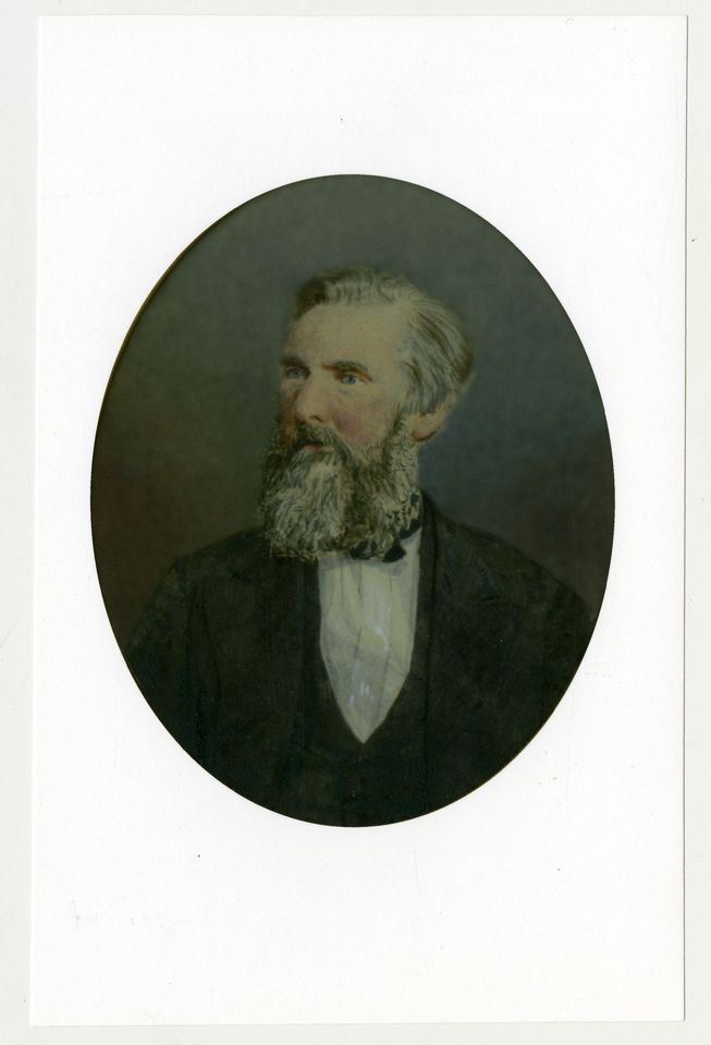Portrait en couleurs d’un homme avec une barbe grisonnante et vêtu d’un complet.