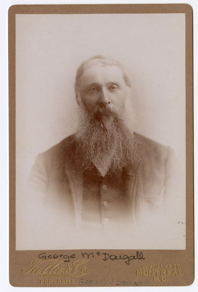 Photographie en noir et blanc d’un homme avec une longue barbe et portant un veston.