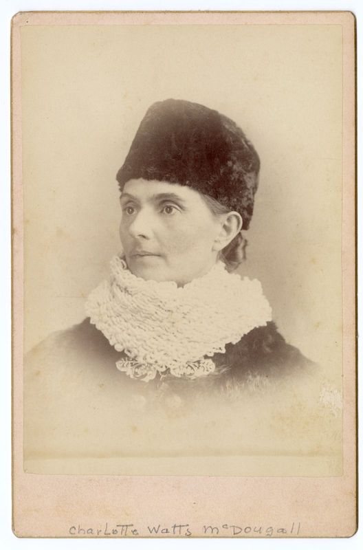 Photographie en noir et blanc d’une femme portant un manteau, un foulard en tricot et un chapeau de fourrure.