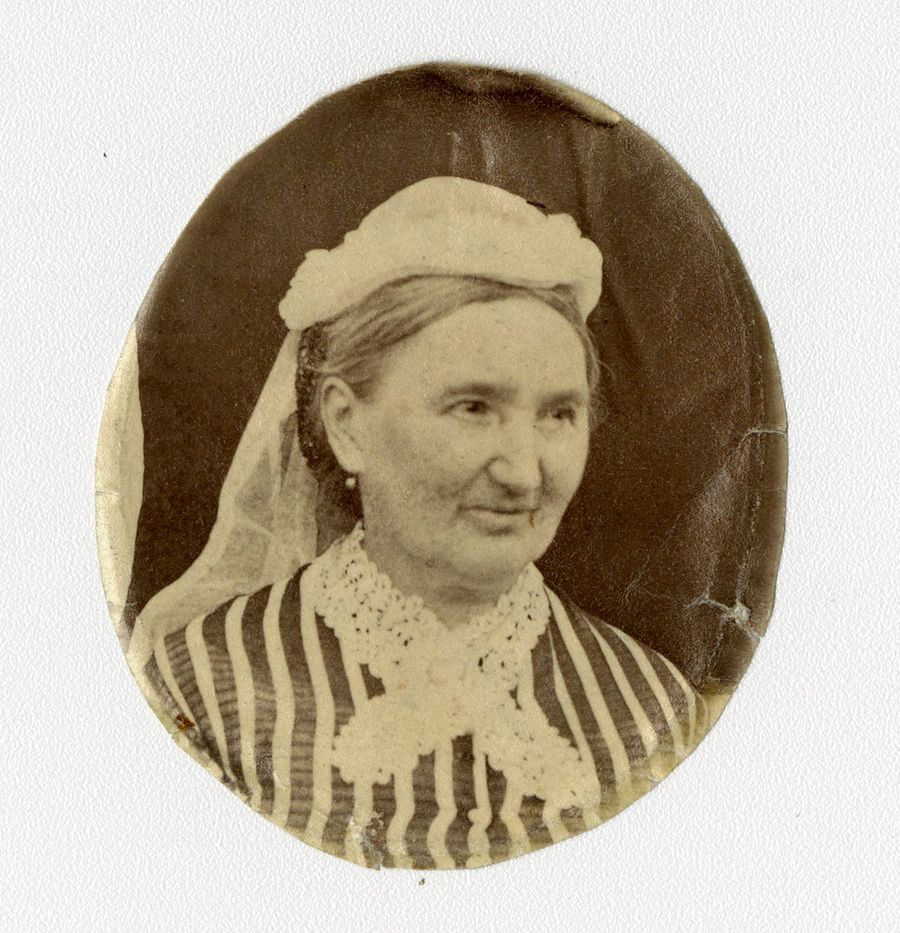 Photographie en noir et blanc d’une femme portant un chapeau ainsi qu’un col de dentelle sur ses vêtements.