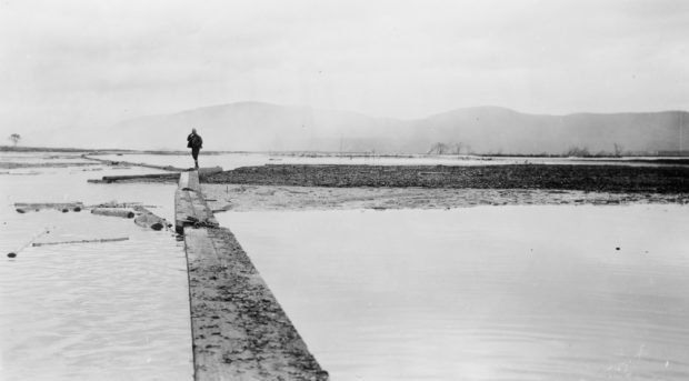 Un homme se tient debout sur une estacade au milieu des eaux brumeuses du Saint-Maurice.
