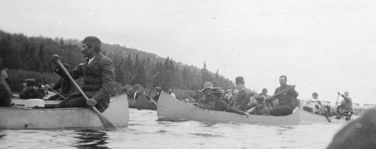 Plusieurs canots remplis d'hommes glissent sur la rivière.