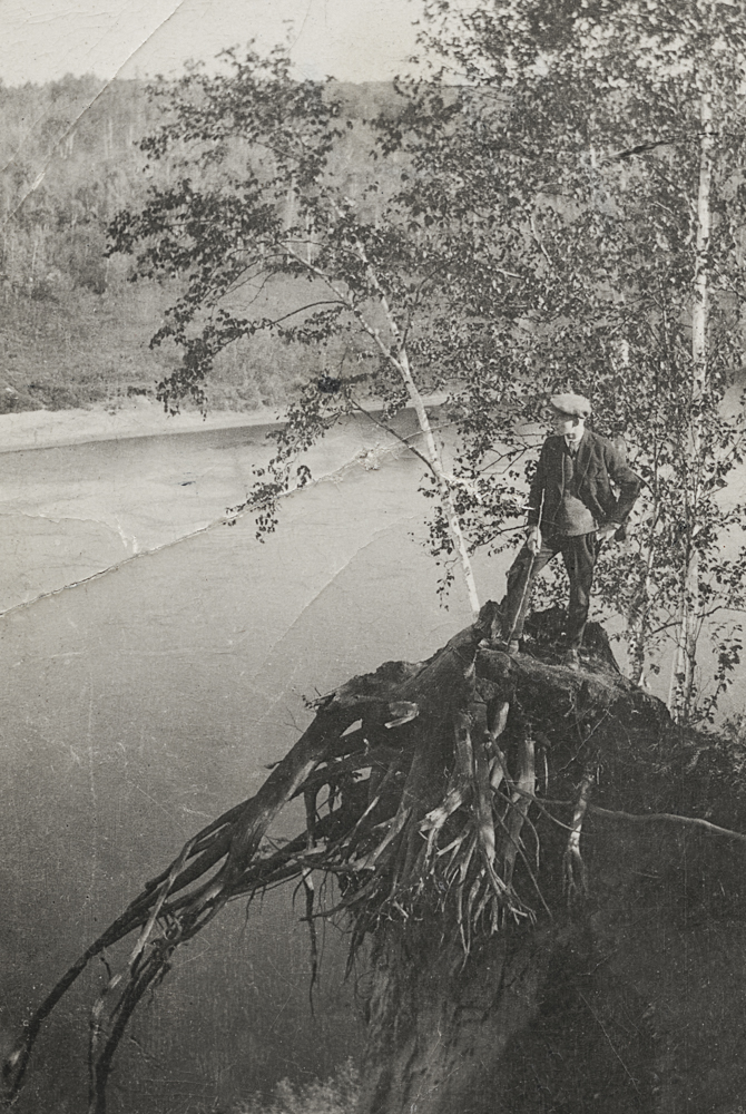 Frank Sutcliffe se tient debout sur une souche surplombant la rivière.