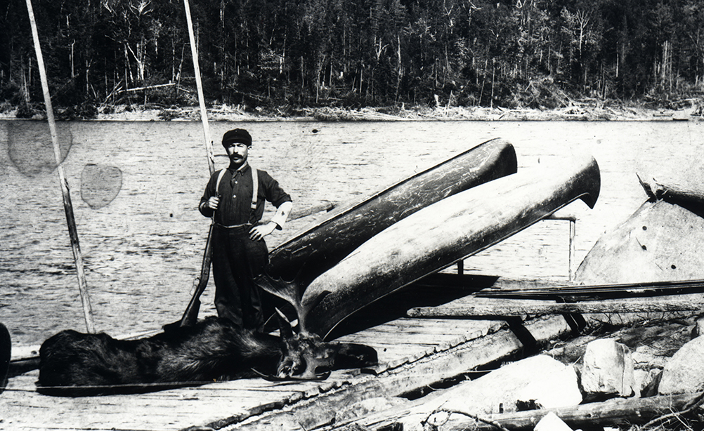 Un homme pose avec une carcasse d'orignal sur un quai devant un lac