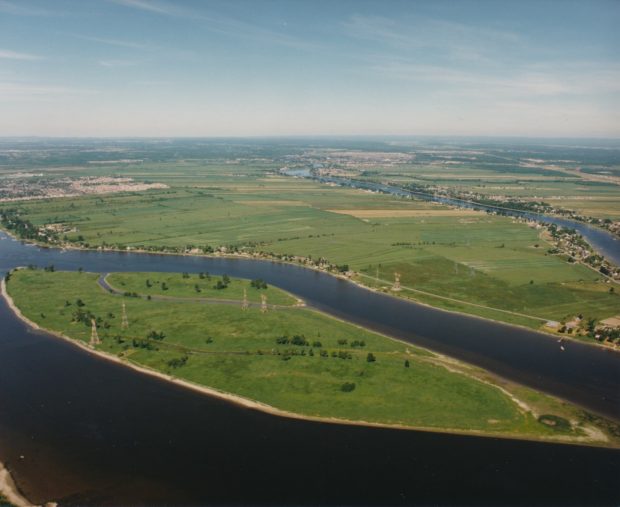 Photographie aérienne en couleur de l’Archipel du Mitan entouré de la rivière des Prairies en été. L’archipel est verdoyant.