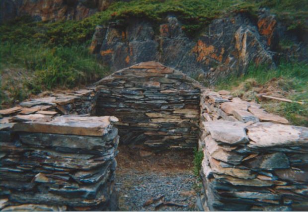 Vue de face des fondations en pierres empilées d’une cave à flanc de colline.