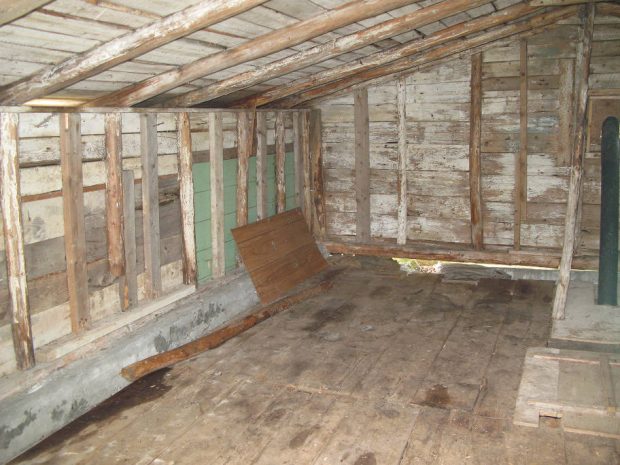 Intérieur de la remise en bois qui surplombe une cave à légumes.