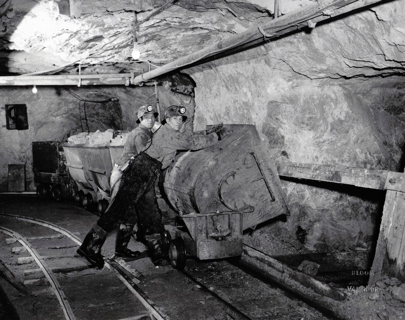 Deux mineurs qui déversent un chariot dans une chute à minerai