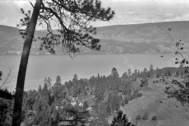 Photo en noir et blanc montrant une vue plongeante sur des édifices et un grand lac.