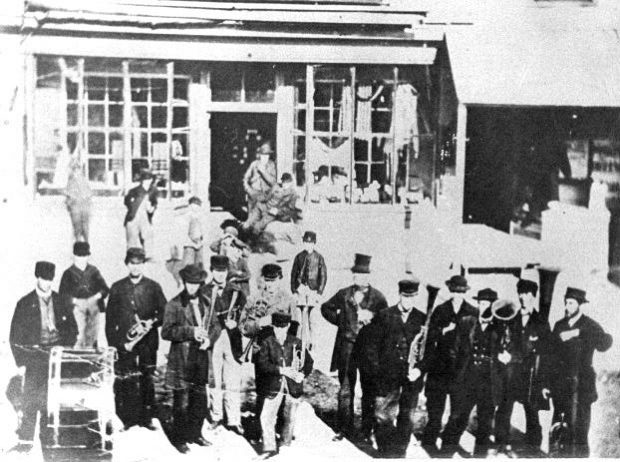 Photo en noir et blanc de l’orchestre de Sharon devant le magasin général du village. Beaucoup de membres de l’orchestre étaient des Enfants de la paix. 