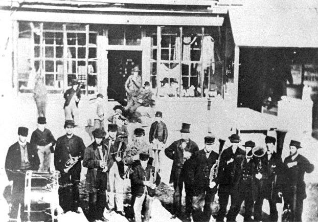 Photo en noir et blanc de l’orchestre de Sharon devant le magasin général du village. Beaucoup de membres de l’orchestre étaient des Enfants de la paix. 