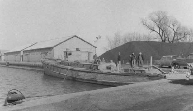  Un groupe d'individus debout près d'un bateau, Harry H, amarré au port d'Oshawa.