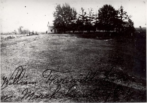 Photographie en noir et blanc d'une maison entourée de grands arbres. Écrit sur la photographie est 'William Farewell house on Marsh land 1844'.