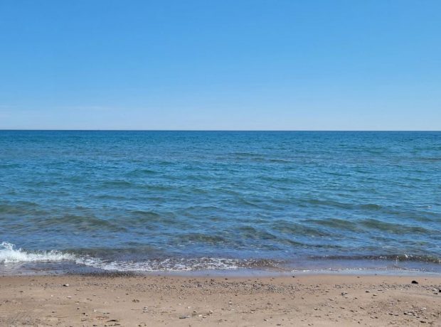 Photographie couleur d'une grande étendue d'eau et de sable.