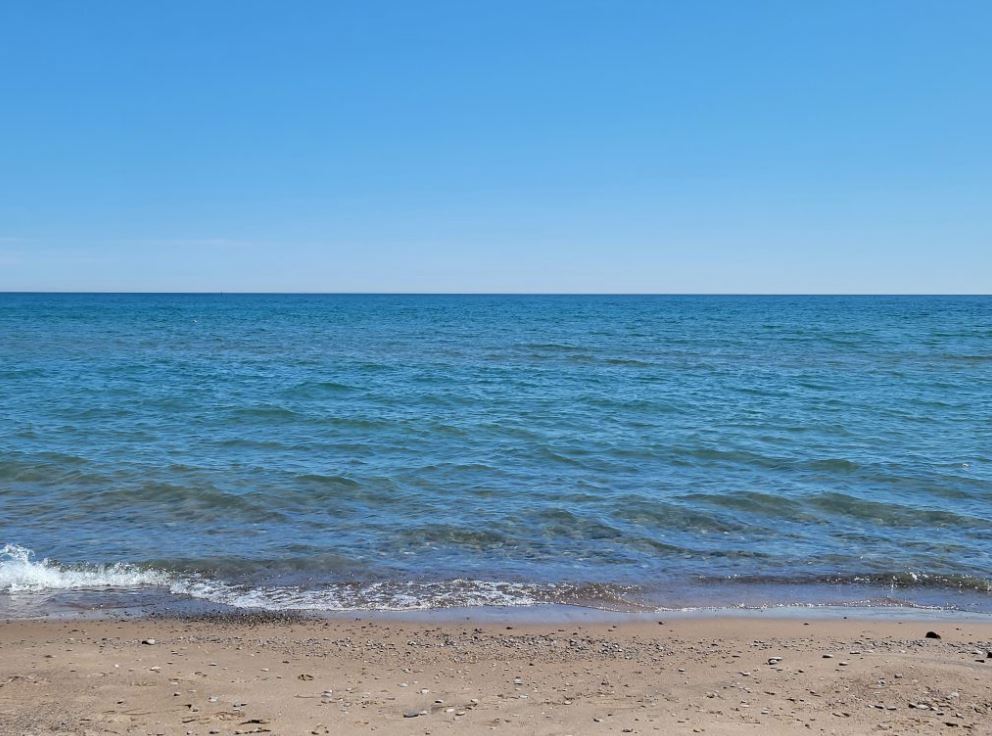 Photographie couleur d'une grande étendue d'eau et de sable.