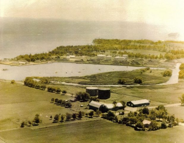 Photographie aérienne en couleur des terres portuaires, présentant quatre bâtiments industriels en forme de cône au premier plan et divers bâtiments industriels à l’arrière-plan.  