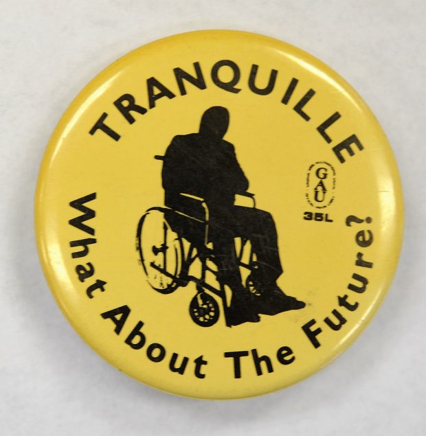 Un macaron jaune et noir avec l’image d’une personne dans une chaise roulante lit « Tranquille On en parle du  futur? » 
