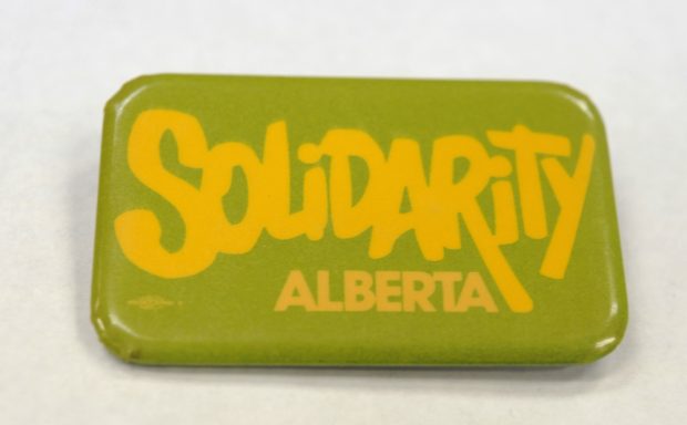 Un macaron vert et jaune indique « Solidarity Alberta » 