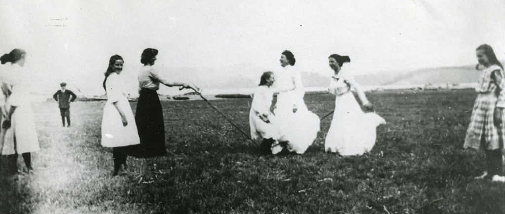 Une photographie noir et blanc des femmes  jouent à la corde à sauter dans un camp.