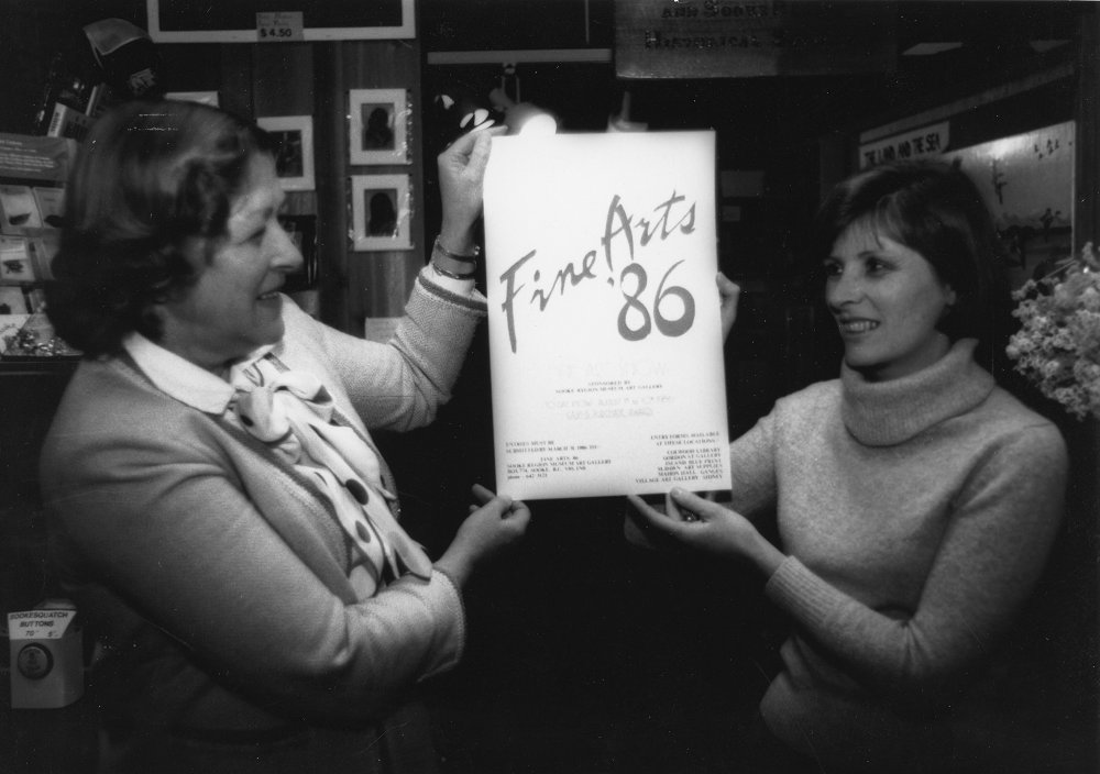 Deux femmes tenant l’affiche de l’Exposition des beaux-arts de Sooke (Sooke Fine Arts Show) de 1986.